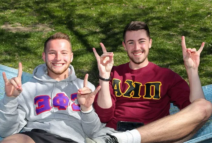 two students with greek life shirts throw their lopes